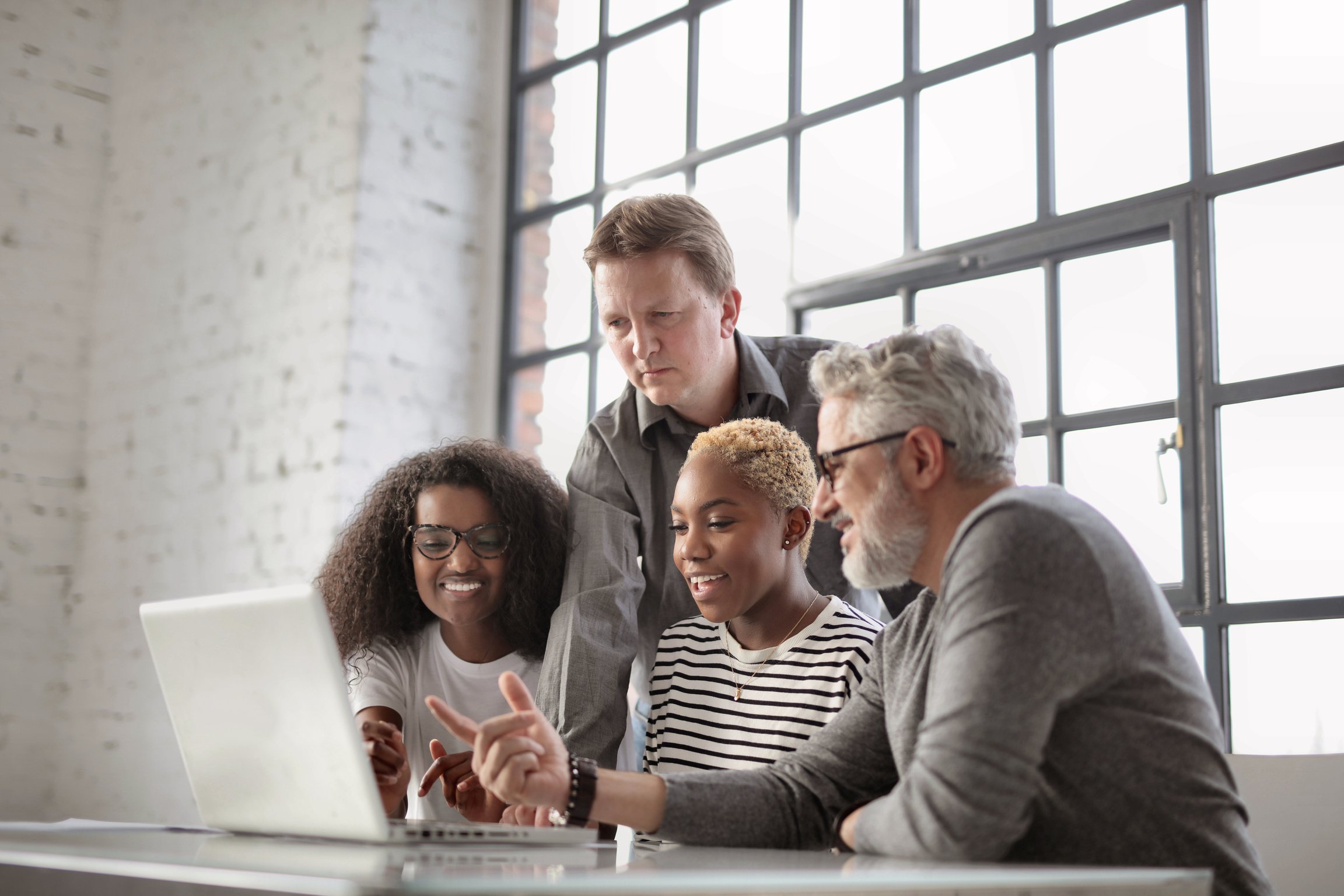 Happy diverse coworkers working on laptop